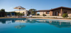 a swimming pool in front of a house with an umbrella at Podere 1248 in Ladispoli