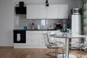 a kitchen with white cabinets and a table with chairs at Apartament Soft 14 in Biała Podlaska