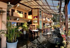 un restaurante con mesas, sillas y plantas en Hotel Norbu House, en McLeod Ganj