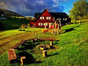 a red house with a playground in a field at Horský Penzion Černava in Horní Malá Úpa +24 photos