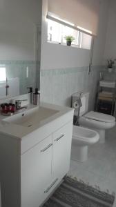uma casa de banho branca com um lavatório e um WC em Quarto/Suite de Charme em Viana do Castelo