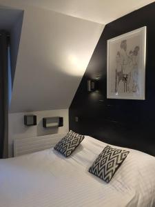 a bedroom with a bed with two pillows on it at Hôtel La Mascotte & Restaurant Bellis Garden in La Baule