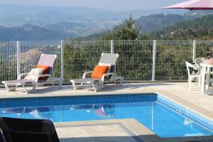 a swimming pool with chairs and a table and an umbrella at Casa da Calçada - a 10 minutos dos Passadiços do Paiva in Cinfães