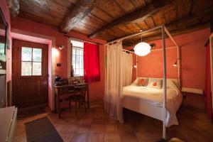 カンネロ・リヴィエーラにあるla vecchia casa rosaのベッドルーム(天蓋付きベッド1台、デスク付)