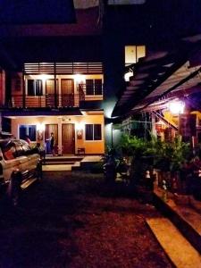 a house with a person standing in front of it at night at Chom Chan Guesthouse & Hostel in Chiang Mai