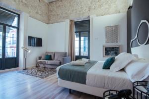 ein Schlafzimmer mit einem großen Bett und ein Wohnzimmer in der Unterkunft Hotel Boutique Alicante Palacete S.XVII Adults Only in Alicante