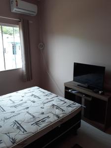 1 dormitorio con 1 cama y TV de pantalla plana en Apartamentos Bombinhas, en Bombinhas