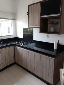 cocina con armarios de madera y encimera negra en Apartamentos Bombinhas, en Bombinhas