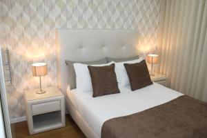 a bedroom with a white bed with two lamps on tables at Casa da Calçada - a 10 minutos dos Passadiços do Paiva in Cinfães