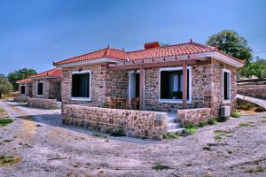 una pequeña casa de piedra con techo rojo en Ktima Kiourelioti, en Skála Sykaminéas