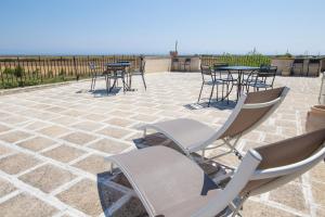 d'une terrasse avec des chaises et des tables. dans l'établissement Agriturismo La Palascìa Masseria Agreste, à Otrante
