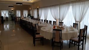 un comedor largo con mesas y sillas blancas en Restauracja Hotel Graal en Targowisko