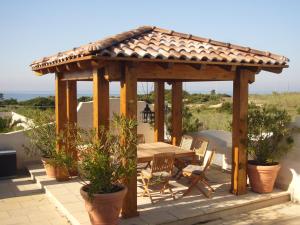 a wooden gazebo with a table and chairs on a patio at Villa I Tamarigi in Maruggio