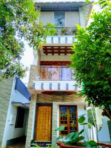 a house with a balcony and two doors and trees at Mary Land Homestay in Trivandrum