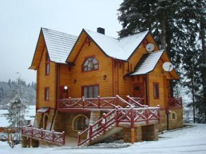 una gran casa de madera con nieve en el techo en Норіс en Migovo