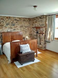 1 dormitorio con cama y pared de piedra en Casa Benaxo, en Currelos