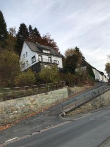 une maison blanche sur le côté d'une route dans l'établissement Ferienhaus Schneeweiß, à Winterberg