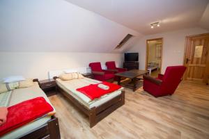a bedroom with two beds and a living room with red chairs at Domek na Kaszubach - Cały dla Ciebie! in Lipnica