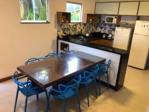 uma cozinha com uma mesa de madeira e cadeiras azuis em Casa Resort em Cacha-Prego