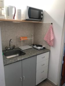 a kitchen counter with a sink and a microwave at Departamento Belgrano III in Salta +8 photos