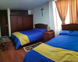 a bedroom with two beds and a cross on the wall at Hotel Casa de Peregrinos in Ipiales