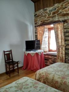 a room with two beds and a table and a window at Casa Benaxo in Currelos