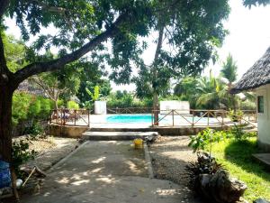 
a pool with a lawn chair and a tennis court at Masai Paradise Cottages in Diani Beach
