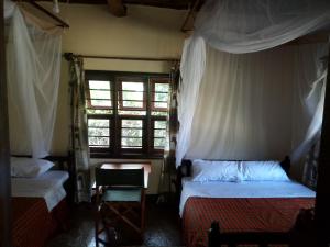 
a bed room with two beds and a window at Masai Paradise Cottages in Diani Beach
