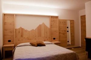 a bedroom with a bed with a large wooden headboard at Hotel Beau Sejour in Arvier