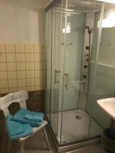 ein Badezimmer mit einer Dusche und einem Stuhl mit Handtüchern in der Unterkunft Restaurant Felsenburg in Kandergrund