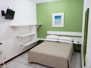 a bedroom with a bed with green walls and white shelves at Pousada Barra Nativa in Florianópolis