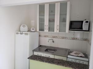 uma pequena cozinha com pia e micro-ondas em Pousada Barra Nativa em Florianópolis