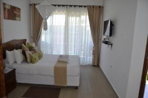 a bedroom with a bed and a large window at Villa Espanhola Bilene in Vila Praia Do Bilene