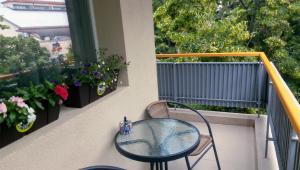 d'une table et d'une chaise en verre sur un balcon fleuri dans l'établissement M&N Central Apartment, à Plovdiv