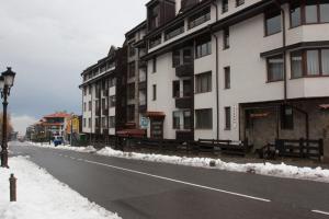 an empty street with snow on the sides of buildings at Feels like Home "Red Tulip" in Bansko