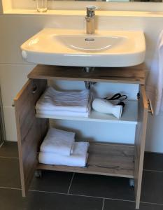 a bathroom with a sink and a shelf with towels at Premium Apartment München Messe in Munich +56 photos