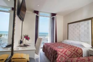Schlafzimmer mit einem Bett, einem Spiegel und einem Fenster in der Unterkunft Hotel Lido in Rimini