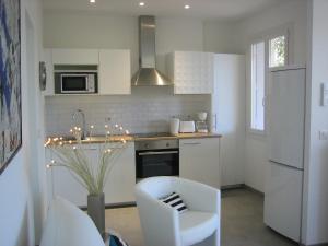 ラ・シオタにあるVILLA DU GOLFE T3 Beaurivageの白いキャビネットと白い椅子付きのキッチン