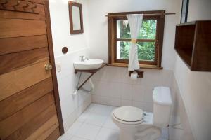 a bathroom with a toilet and a sink and a window at Posada del Cerro in El Remate
