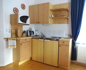 eine Küche mit Holzschränken und einem Waschbecken in der Unterkunft Mitschighof - Apartments und Pension - Heidis-Welt, Mitschig in Hermagor