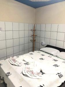 um quarto com uma grande cama branca com lençóis pretos e brancos em Hotel Fortaleza III Manaus em Manaus