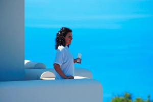 eine Frau, die auf einem Bett sitzt und ein Glas Wein hält in der Unterkunft Kallisti Hotel in Folegandros Chora + 23 Fotos
