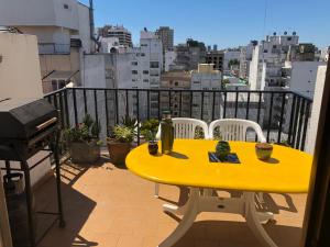une table jaune sur un balcon avec vue sur la ville dans l'établissement El Reino MdQ, à Mar del Plata