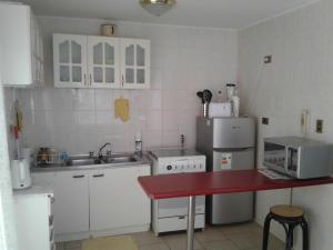 cocina con electrodomésticos blancos y encimera roja en Casa Bahia Inglesa, en Bahía Inglesa