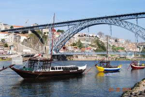 drei Boote im Wasser unter einer Brücke in der Unterkunft Oporto Vasconcelos Guest House in Vila Nova de Gaia