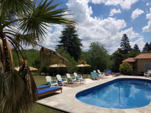 una piscina con sillas y sombrillas junto a una casa en Cabañas Villa Gloria en Villa Giardino
