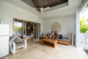 two people sitting on a couch in a living room at Tenang Villas in Nusa Lembongan