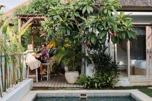 a man and woman sitting on a porch next to a pool at Tenang Villas in Nusa Lembongan