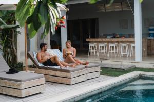a man and a woman sitting in a chair next to a pool at Tenang Villas in Nusa Lembongan