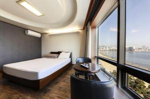 a bedroom with a bed and a large window at Bridge Hotel in Busan